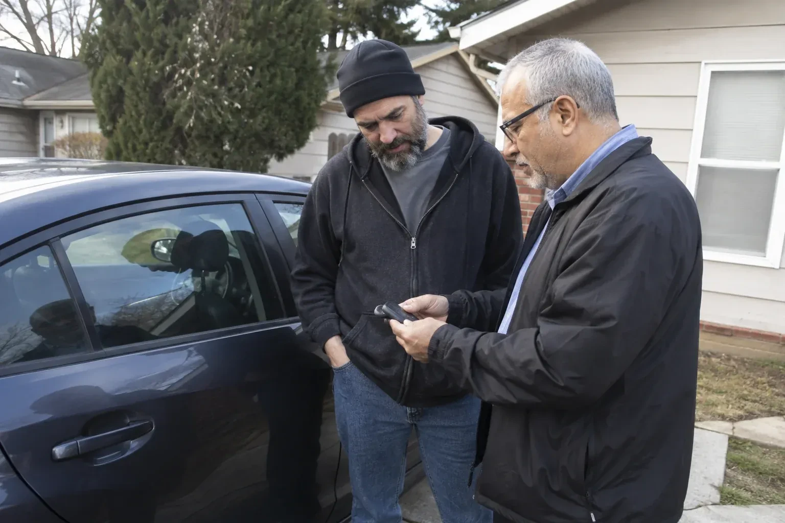 Two adults discussing a key fob beside a parked car. — Car Lockout Service, London